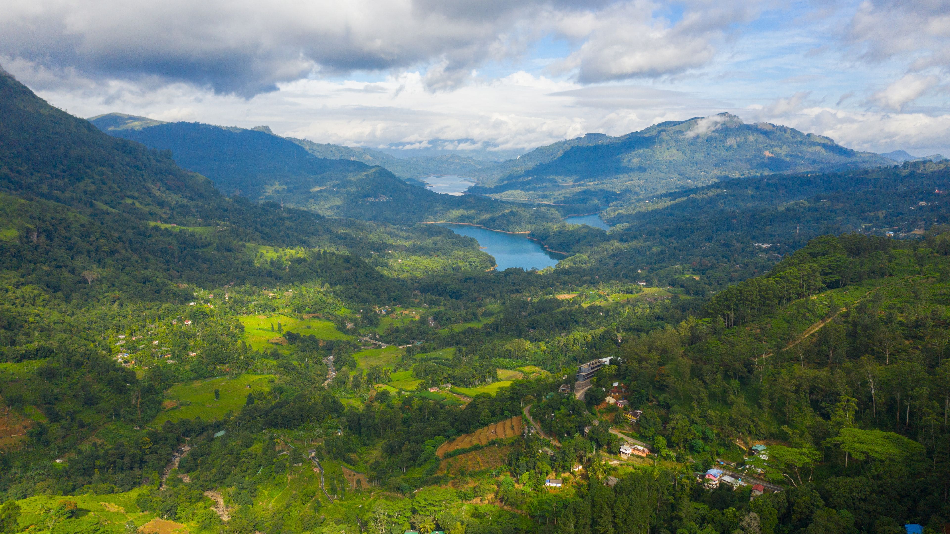 Un paysage montagneux avec un lac et quelques maisons dispersées.