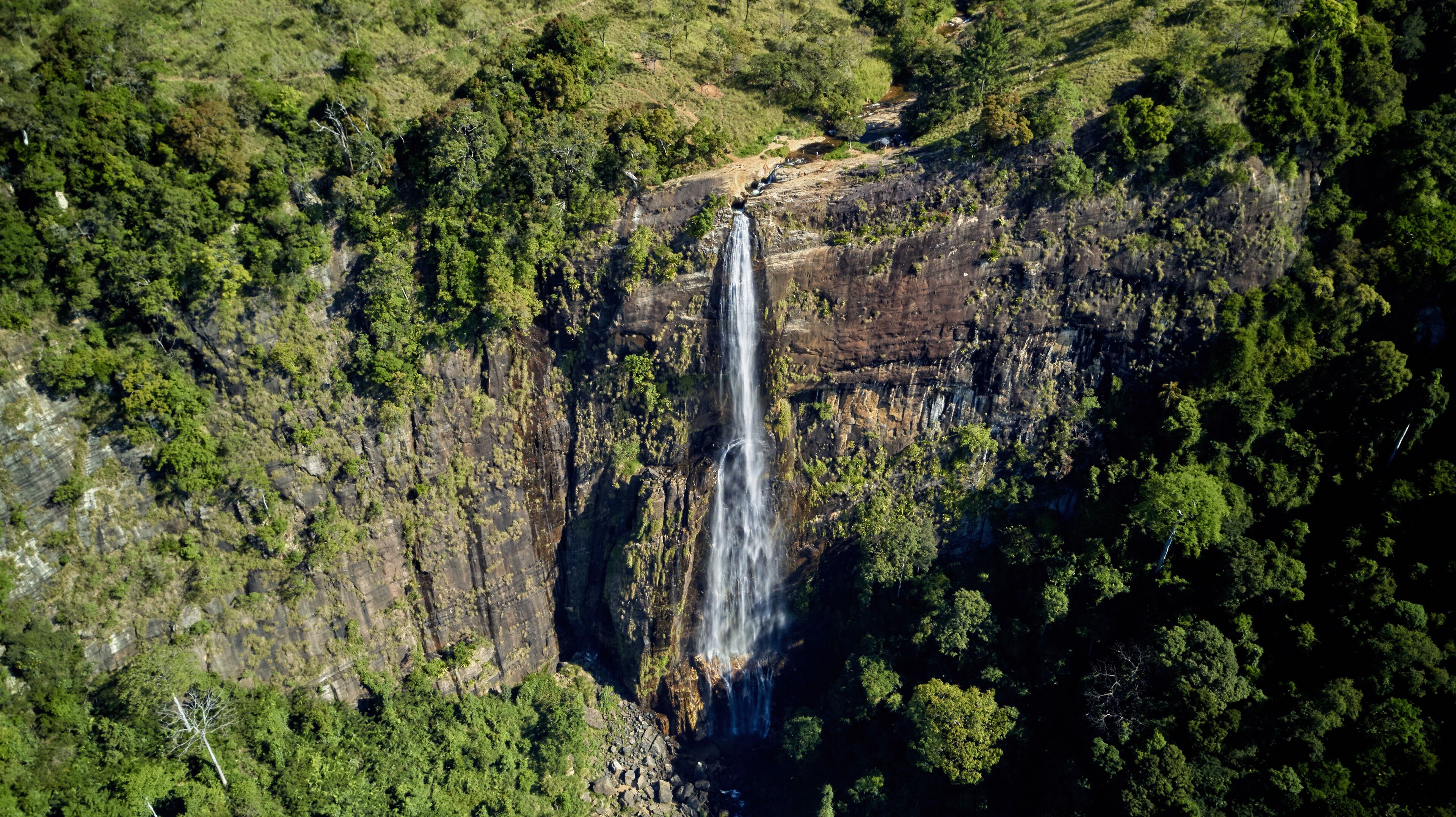 A waterfall cascading down a rocky cliff surrounded by dense green forest.