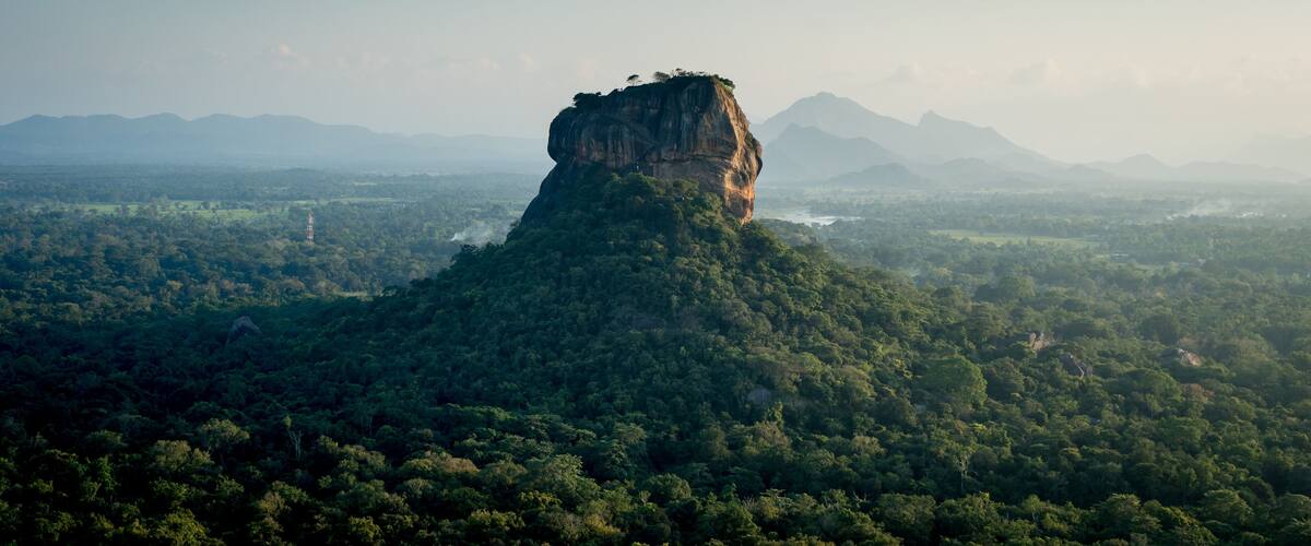 A forested mountain with a prominent rock formation.
