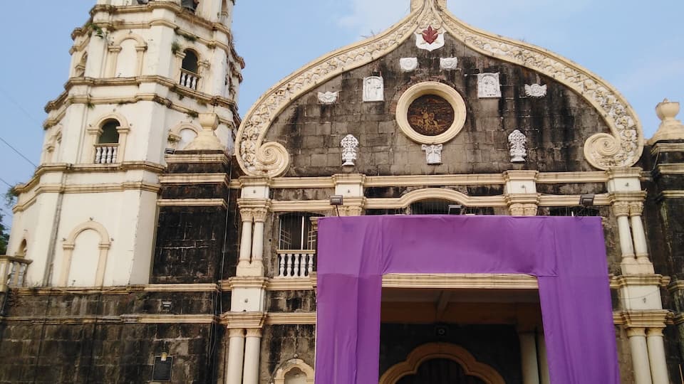 A historic church with a bell tower and a large purple entrance.