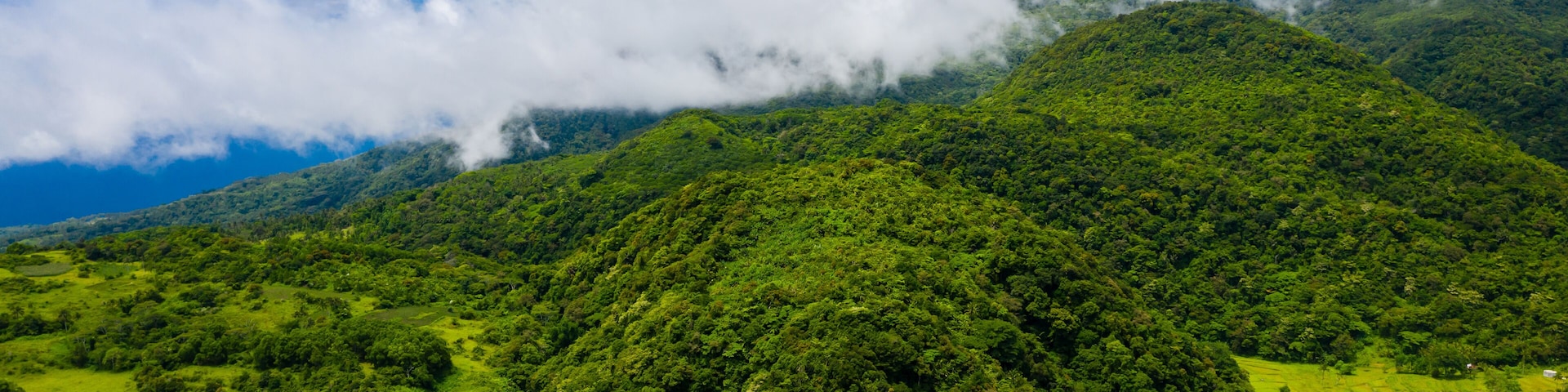 Aerial drone view of clouds over rural farmland and Mount Mambajao on Camiguin island, Philippines