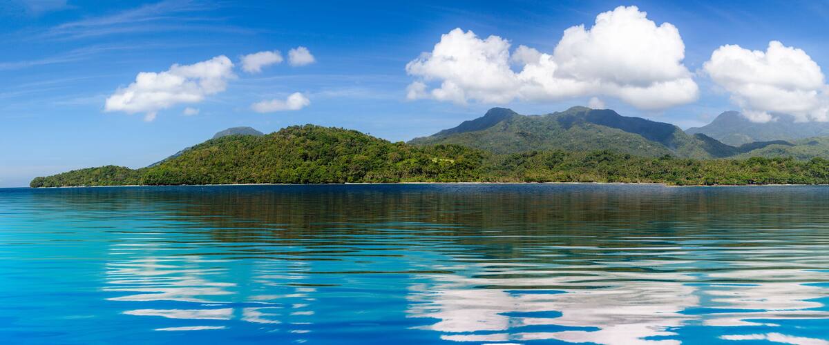 A tropical island with clear turquoise waters and lush green mountains.