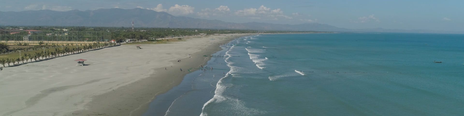 Aerial view of sandy beach Lingayen with fishermen using nets for fishing on the island Luzon, Philippines. Seascape, ocean and beautiful beach.