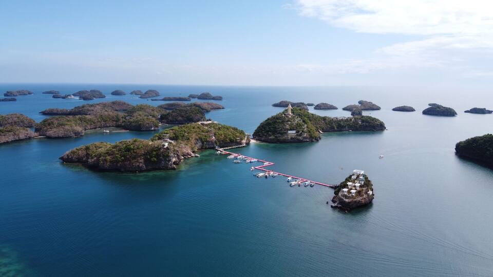 A coastal landscape with multiple small islands connected by a red pier.