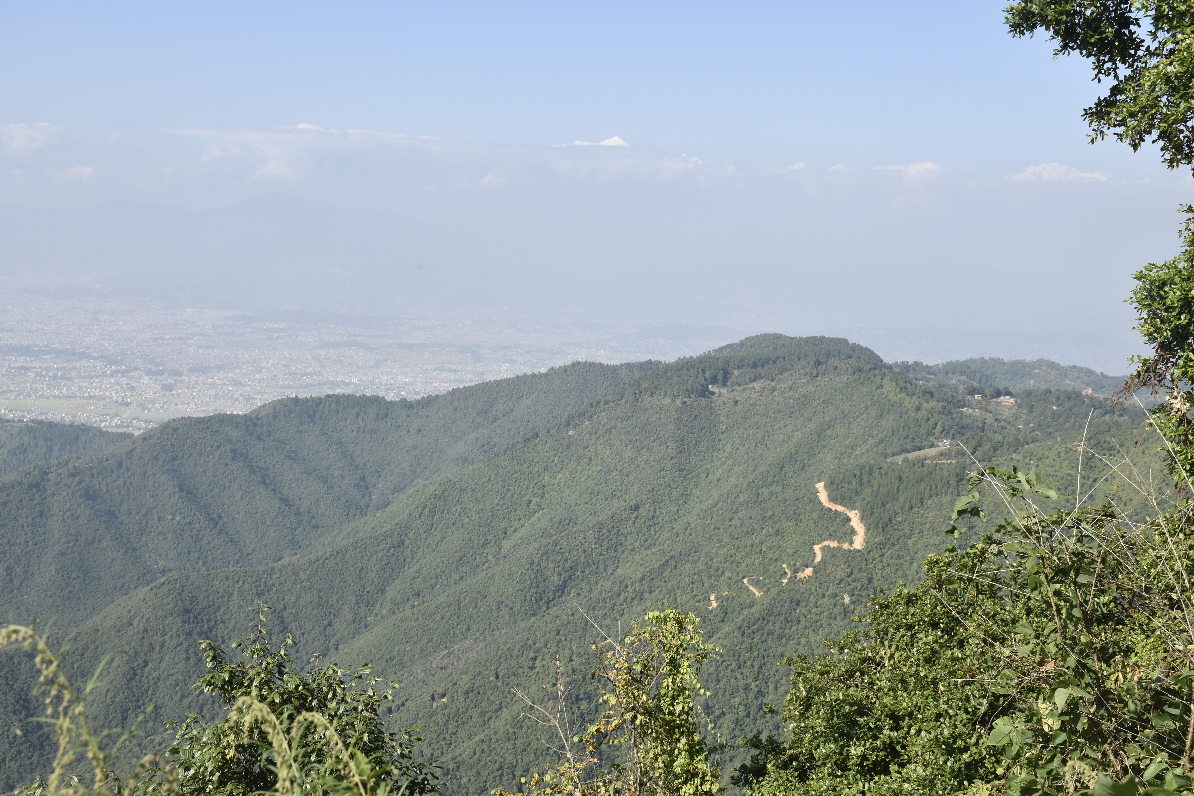 A mountainous landscape with dense green forests and a winding river.