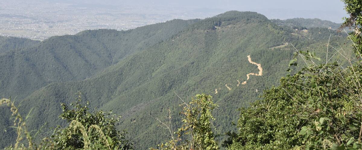 A mountainous landscape with dense green forests and a winding river.