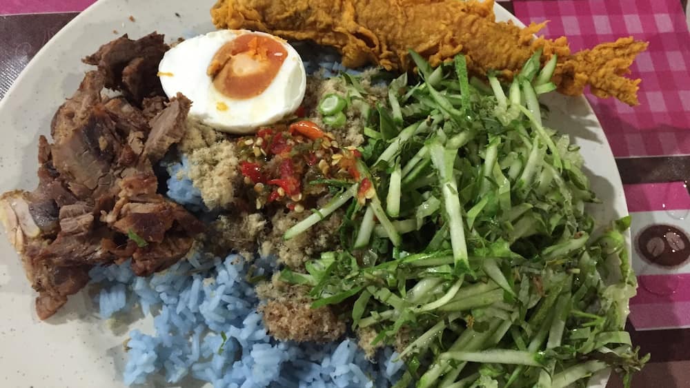 If you are a tourist or just feeling like wanting to try something unique go for this salad rice (Nasi Kerabu). Mix all the ingredients well preferably with hands. Eating with your hand is the norm here. Steal a glance and see how the locals did it.