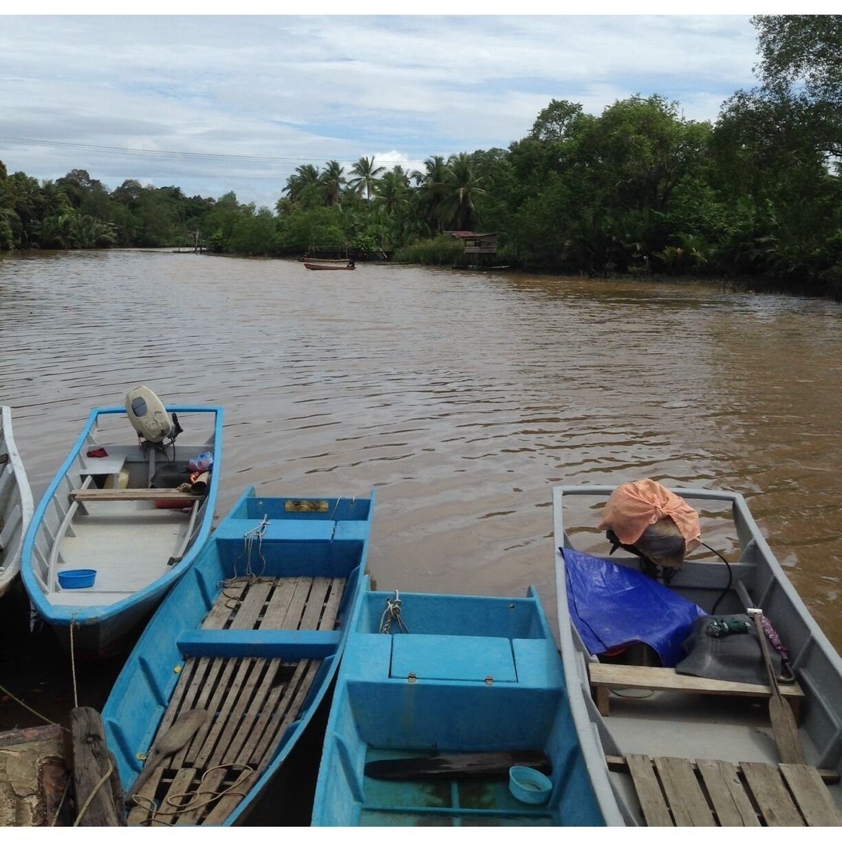 A calm river with several small boats docked along the shore.
