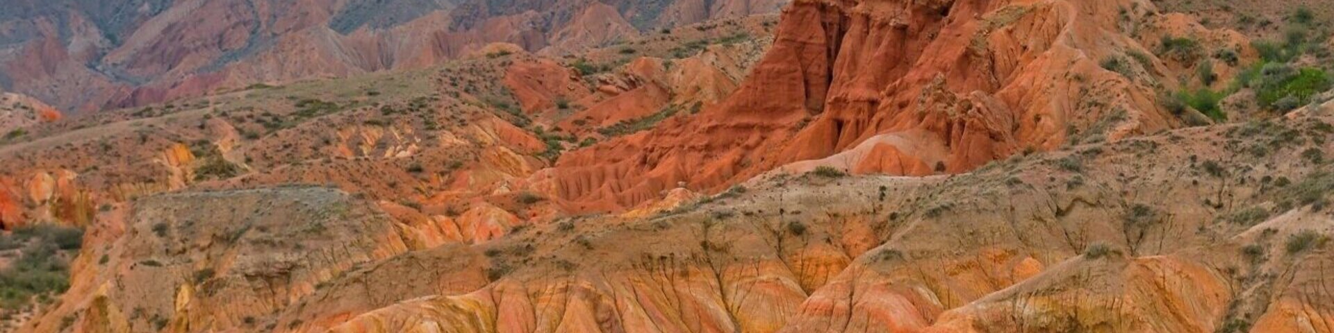Un paisaje agreste con formaciones rocosas estratificadas y vegetación escasa.