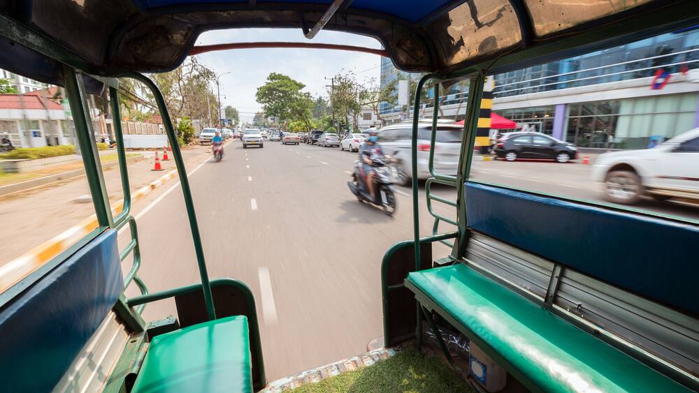 View of traffic on a street from the back of a songthaew (pick-up or small truck with benches along the sides) in Vientiane, Laos, on a sunny day., Shutterstock ID 1216732732, Purchase Order: -