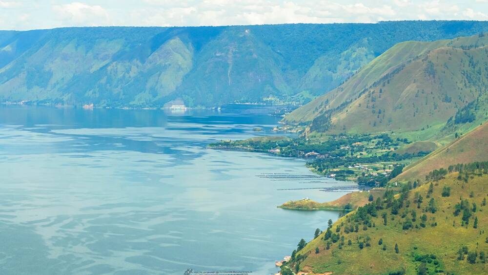 Panoramic aerial drone view of Toba Lake with blue water at Pangururan in Samosir Island, Sumatra Utara, Indonesia