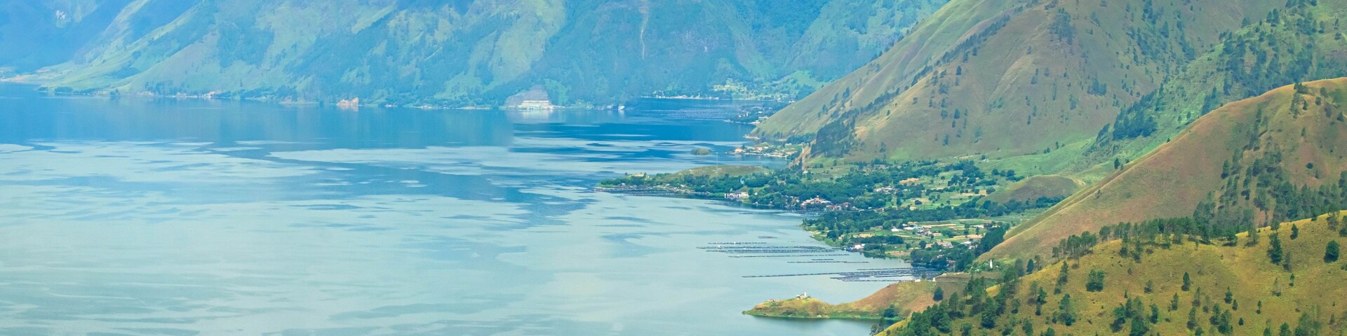 Panoramic aerial drone view of Toba Lake with blue water at Pangururan in Samosir Island, Sumatra Utara, Indonesia