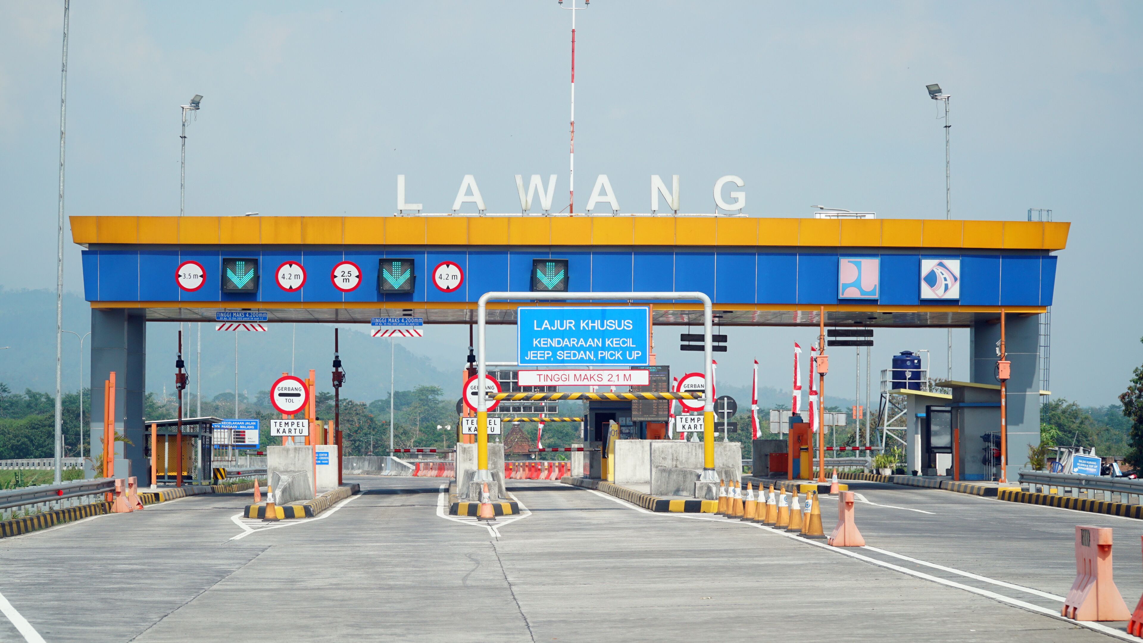 A toll booth with 'LAWANG' signage, multiple height restriction signs, and a 'TERMINAL KARTU' sign.