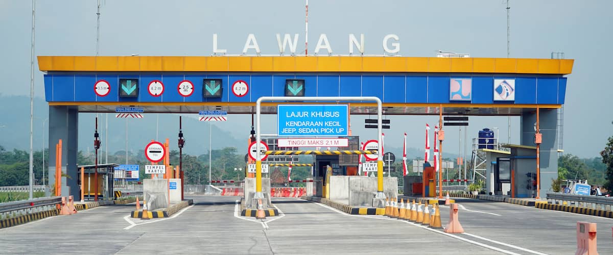 A toll booth with 'LAWANG' signage, multiple height restriction signs, and a 'TERMINAL KARTU' sign.