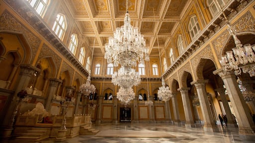 An ornate hall with a large chandelier, intricate ceiling designs, and classical architecture.