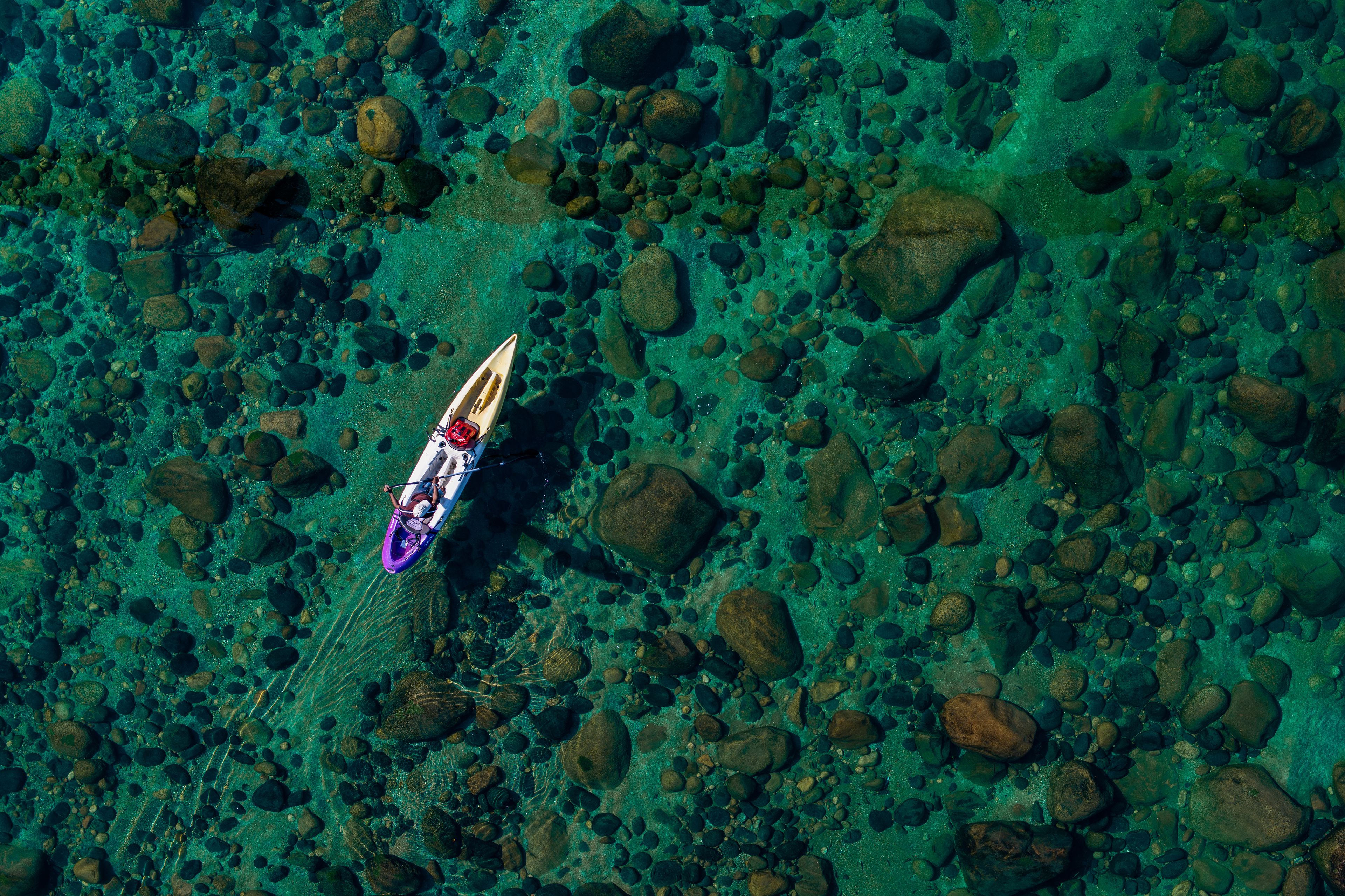 Vista aèria d'una piragua sobre un llit fluvial rocós.