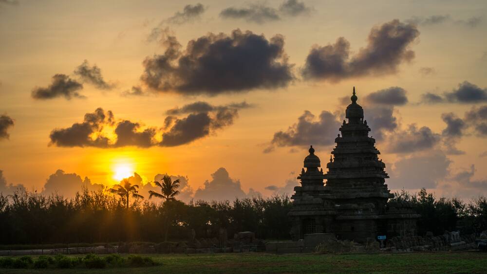 A temple complex at sunset with the sun behind clouds.