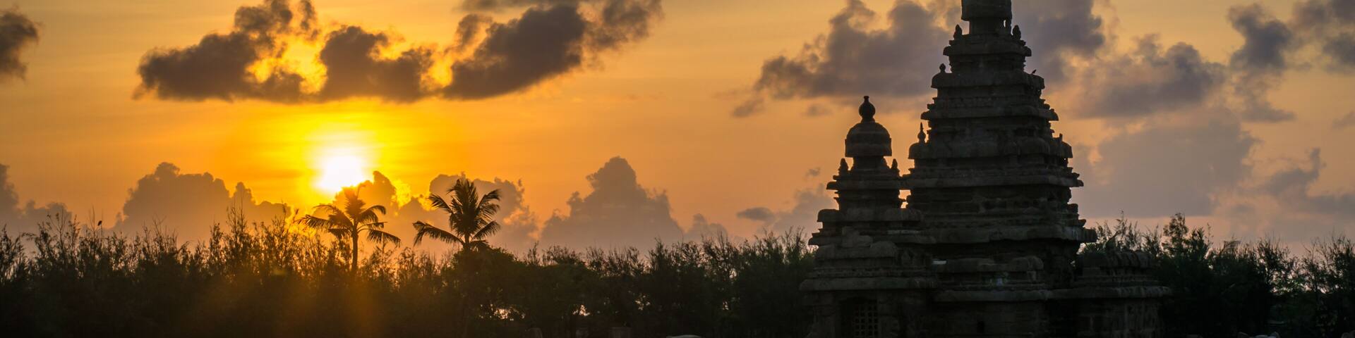 A temple complex at sunset with the sun behind clouds.