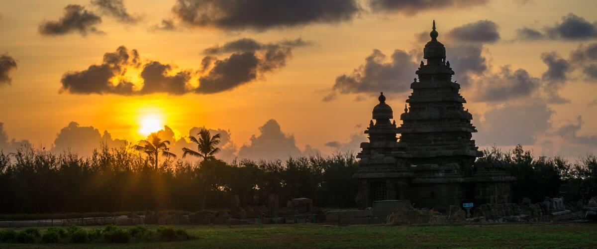 A temple complex at sunset with the sun behind clouds.