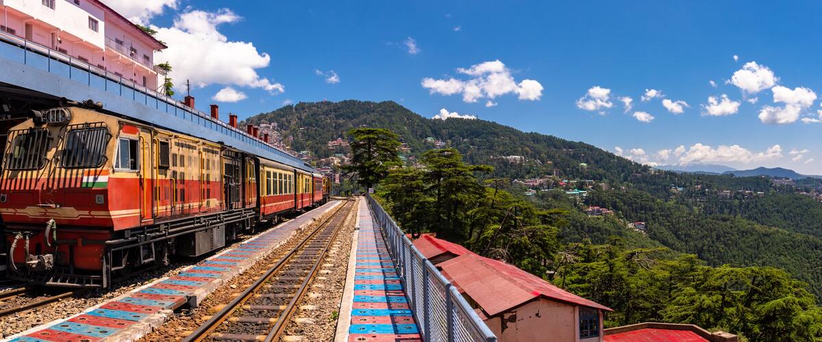A train on tracks with a mountainous landscape in the background.