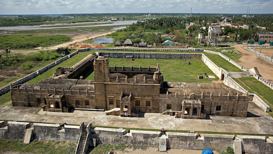 An ancient fortress with a large central tower, surrounded by walls and smaller buildings.