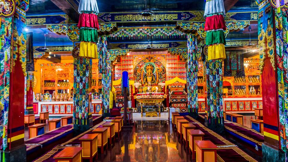 A brightly decorated temple interior with colorful pillars, ornate decorations, and a central statue.