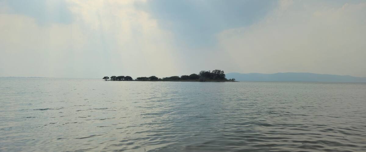 A calm body of water with a small island in the distance.
