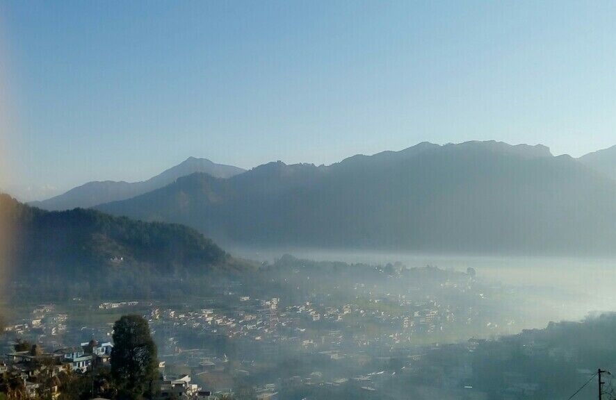 A misty mountain landscape with a town in the valley below.