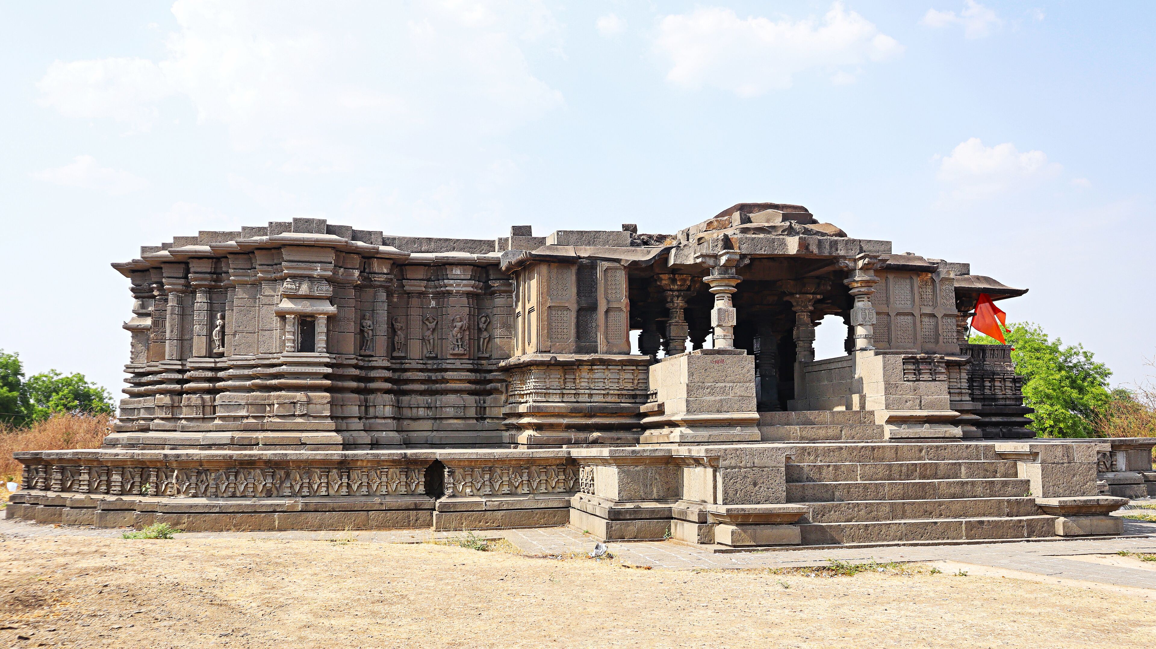 An ancient temple with intricate carvings and a flag.