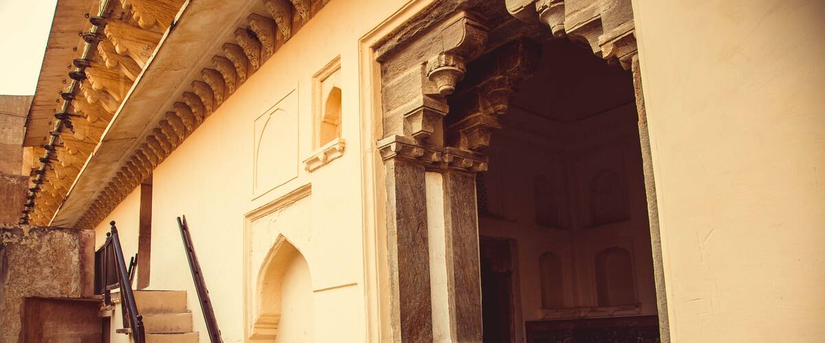 A historic building with ornate arches, a staircase, and a wooden door.