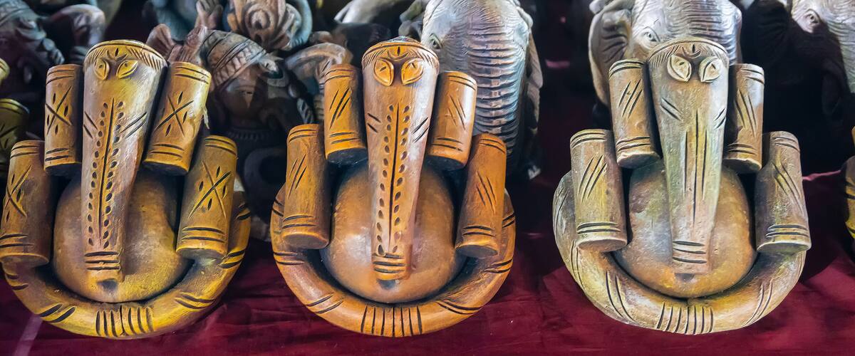 A collection of intricately carved wooden sculptures, including elephant and deer figures, displayed on a red fabric surface.