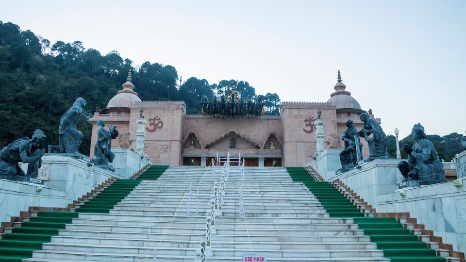 A temple with steps leading up to a central shrine, flanked by statues and domed structures.