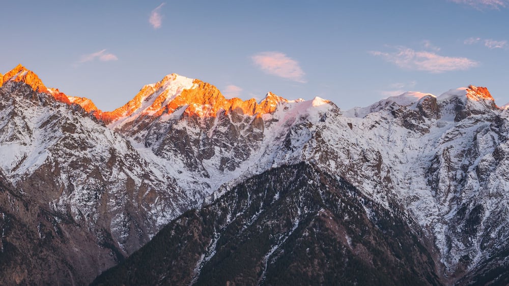 A snow-covered mountain range with sharp peaks and a clear sky.
