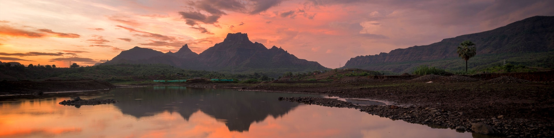 Un río tranquilo que refleja el cielo, rodeado de montañas y vegetación escasa.