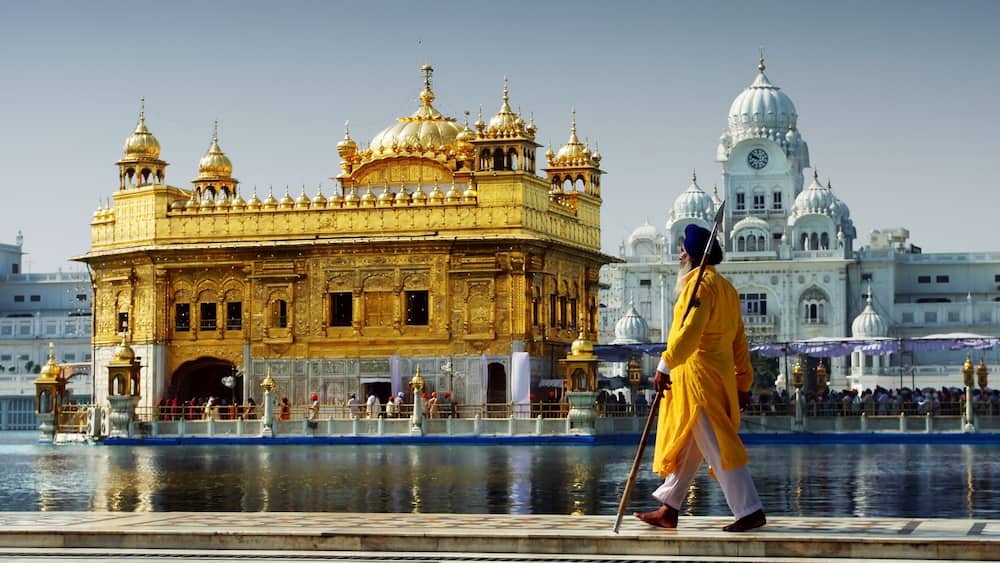 The Golden Temple with a person in traditional attire walking in front.