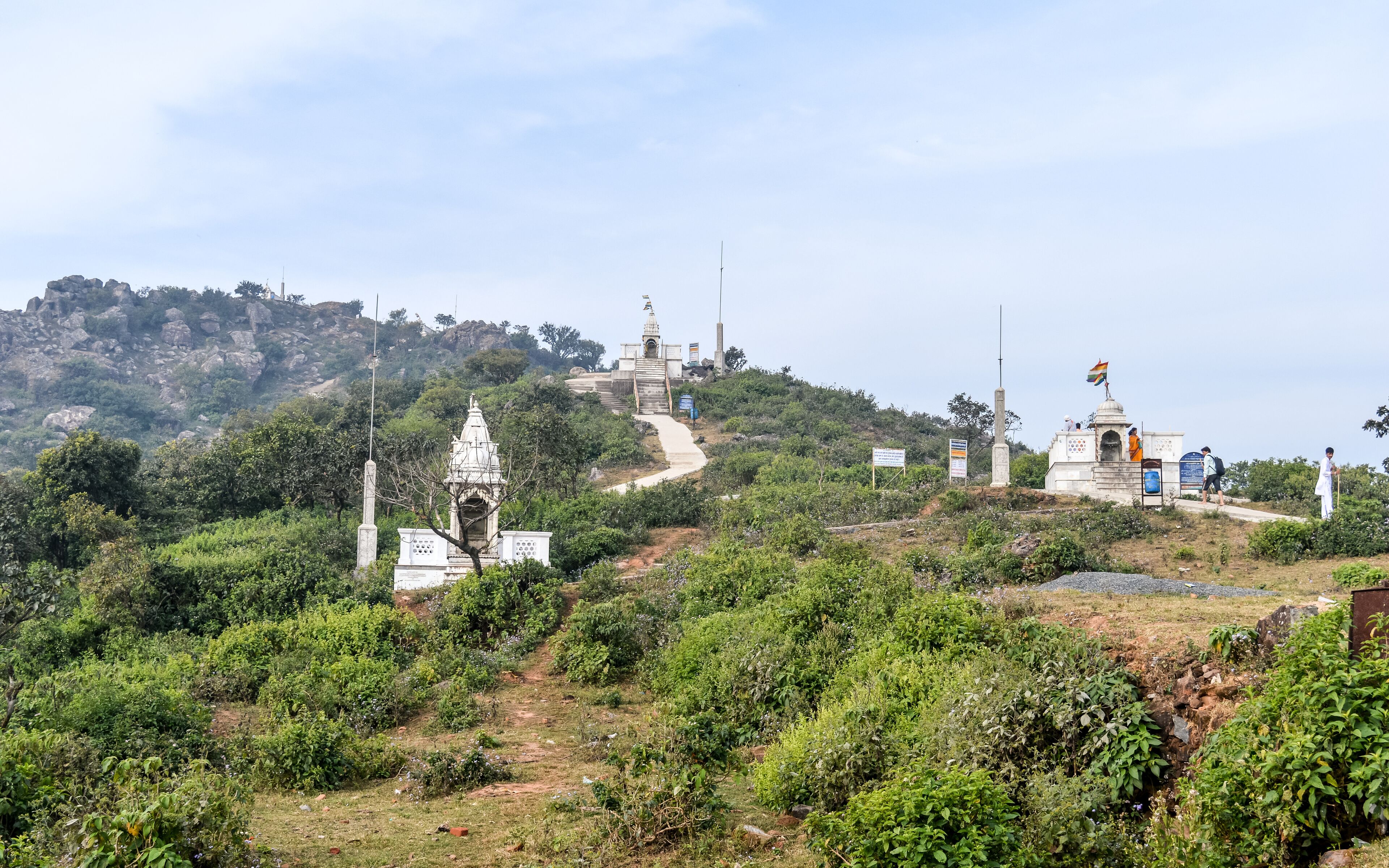 A hilly landscape with a temple, a flagpole, and a memorial.