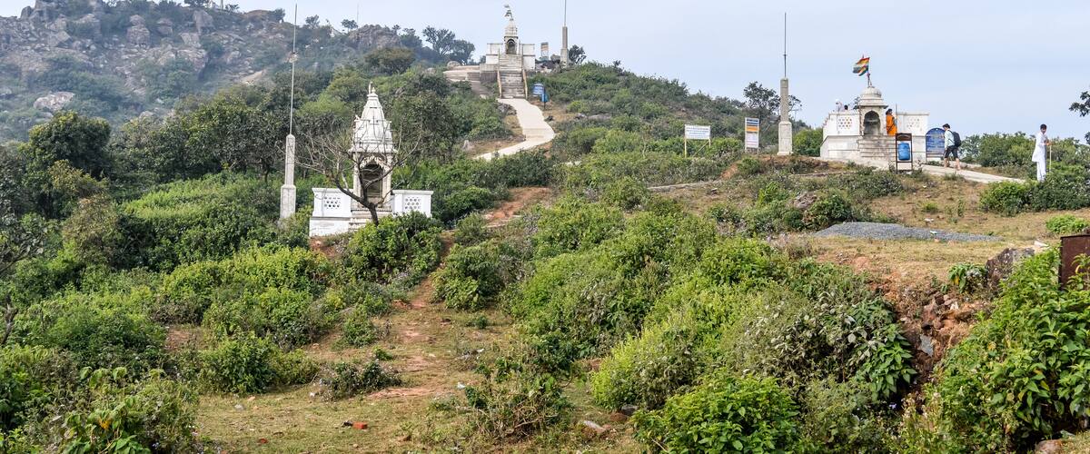 A hilly landscape with a temple, a flagpole, and a memorial.