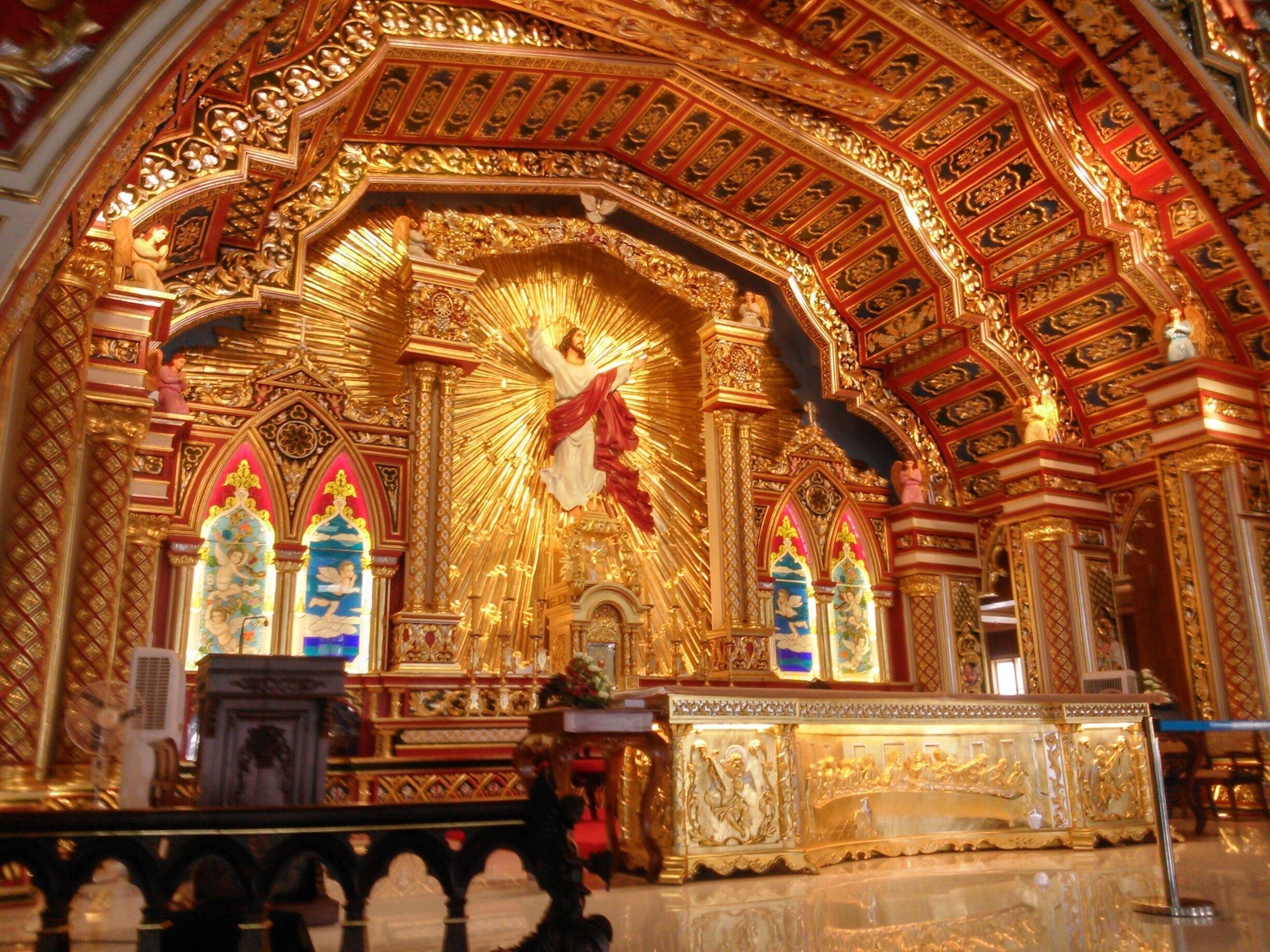 An ornate religious interior with golden decorations, a central figure, and a high ceiling.