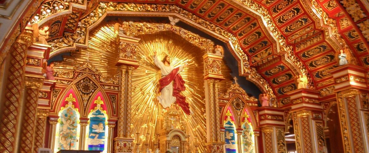 An ornate religious interior with golden decorations, a central figure, and a high ceiling.
