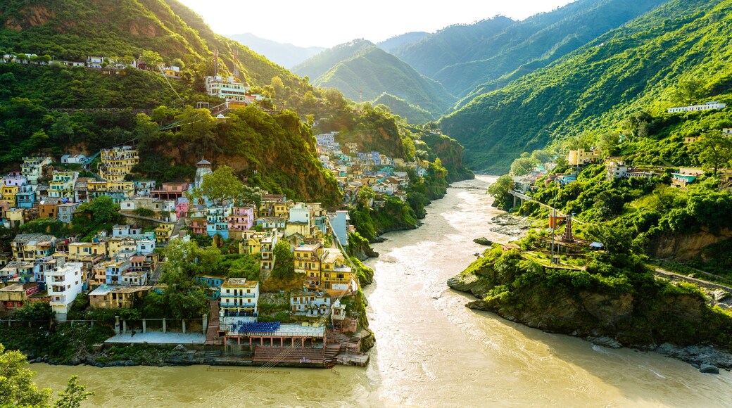 Confluence of two rivers Alaknanda and Bhagirathi give rise to the holy river of Ganga / Ganges at one of the five Prayags called Dev Prayag. Lush greenery in monsoons on the mountains. sunrise. India