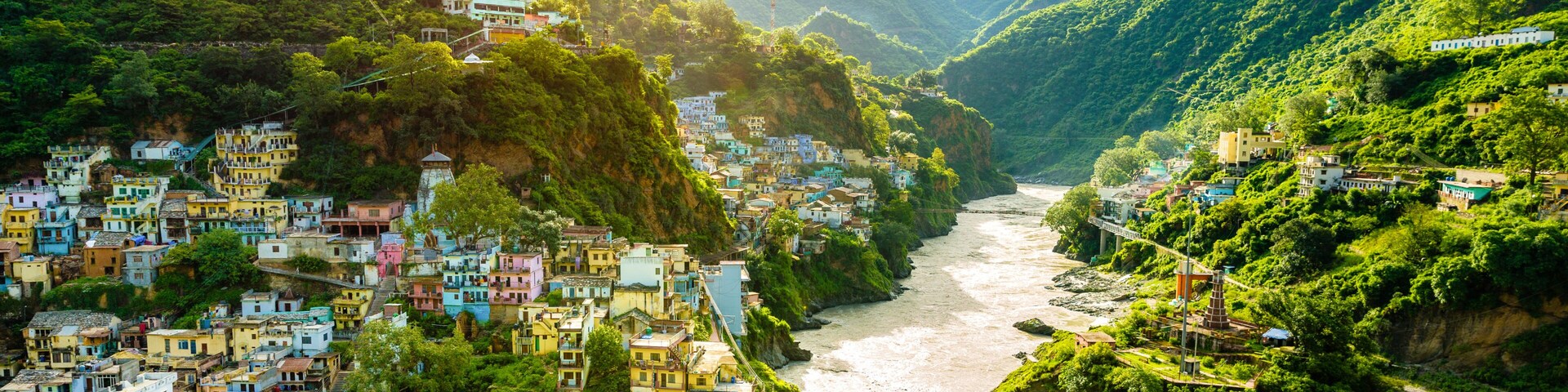 Confluence of two rivers Alaknanda and Bhagirathi give rise to the holy river of Ganga / Ganges at one of the five Prayags called Dev Prayag. Lush greenery in monsoons on the mountains. sunrise. India