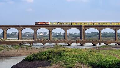 On its inaugural run, super-fast Duronto express train crossing an old stone arc bridge in Daund, Maharashtra, India