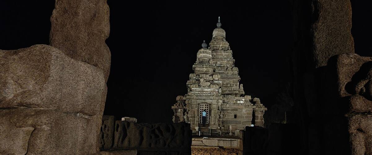 A stone temple with a spire, surrounded by large rock formations.