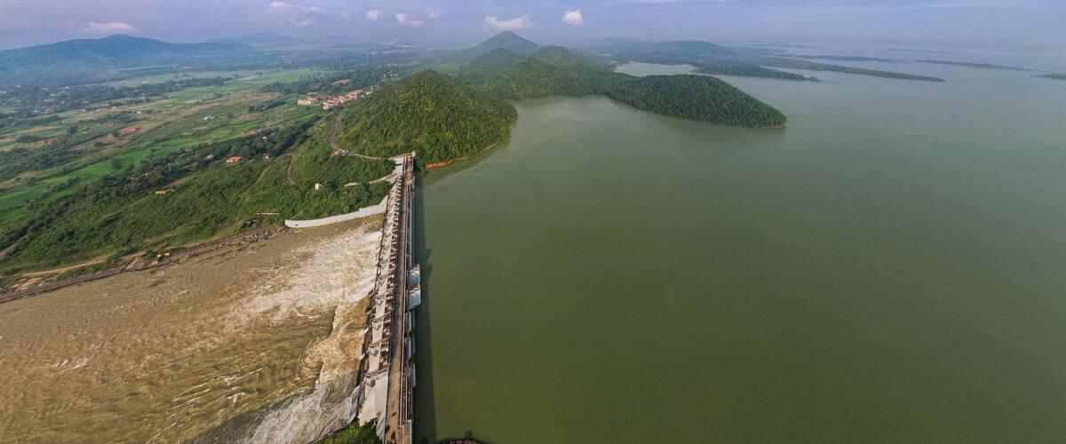 A dam with a reservoir, a bridge, and a mountainous landscape.