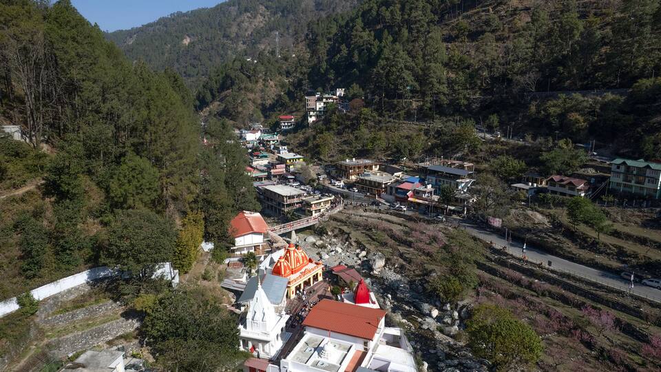 A mountainous village with terraced fields, a prominent church with a red dome, and a winding road.