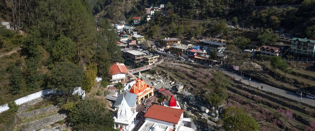 A mountainous village with terraced fields, a prominent church with a red dome, and a winding road.