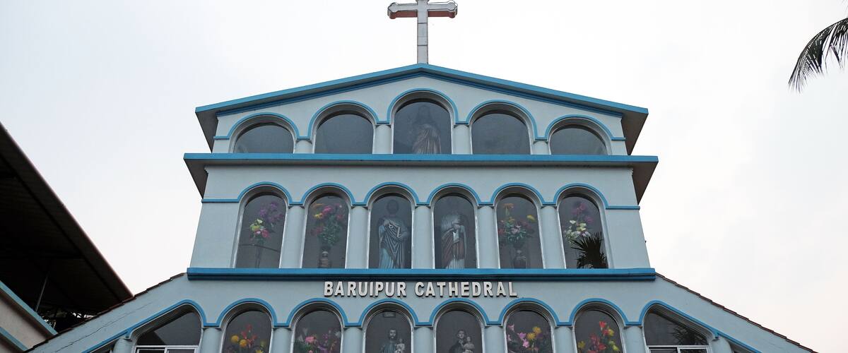 Baruipur Cathedral with a cross on top and statues in the windows.