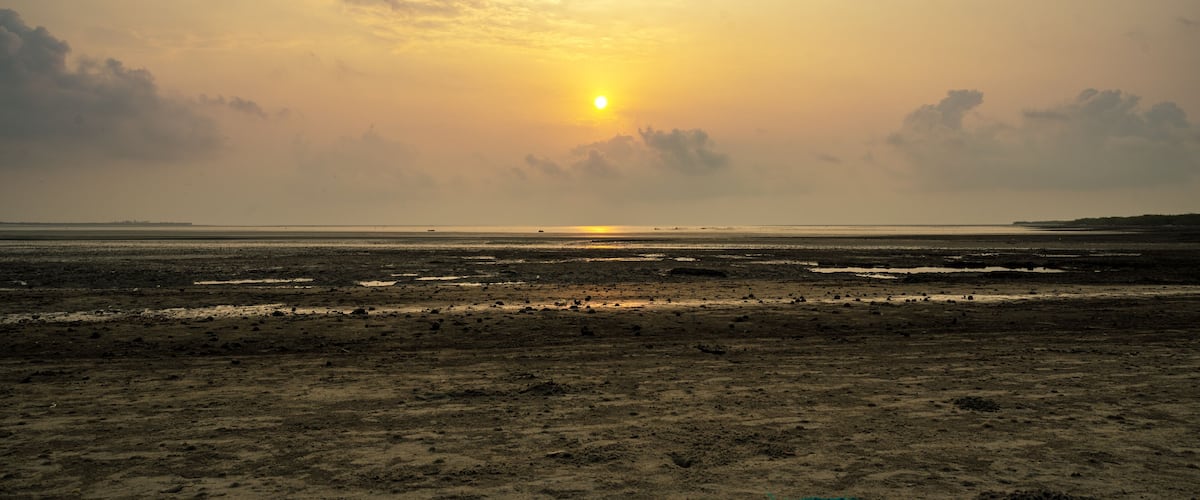 A sunset over a barren landscape with a flat horizon.