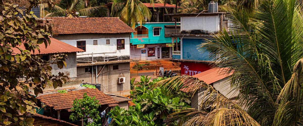 A tropical village with colorful houses, palm trees, and a hilly backdrop.