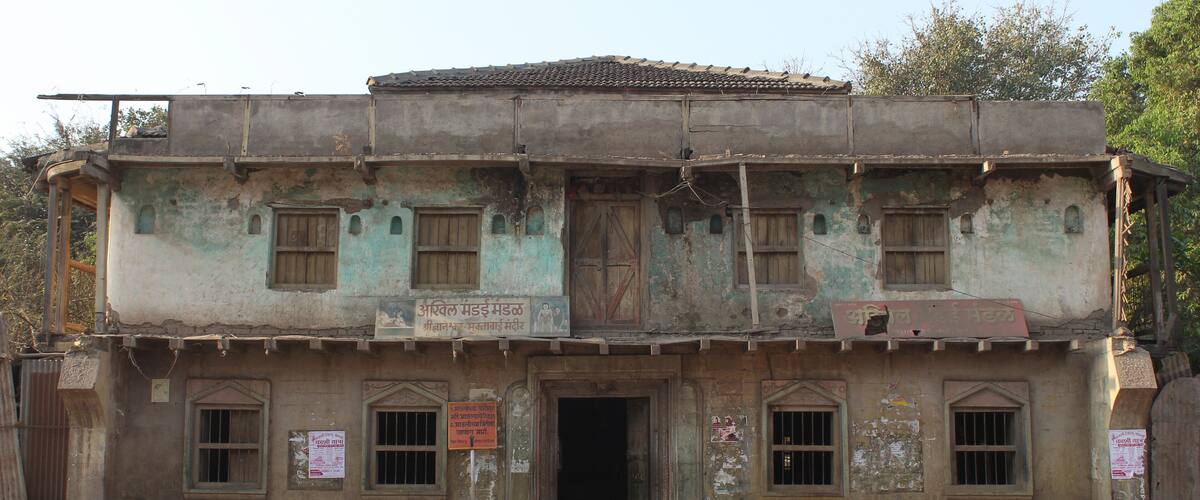 A two-story building with a weathered facade, multiple windows, and a signboard.